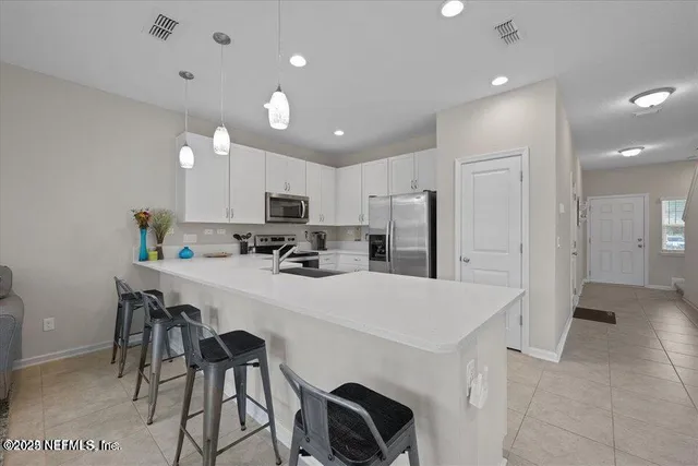a kitchen with kitchen island a stove a refrigerator a sink and white cabinets with wooden floor
