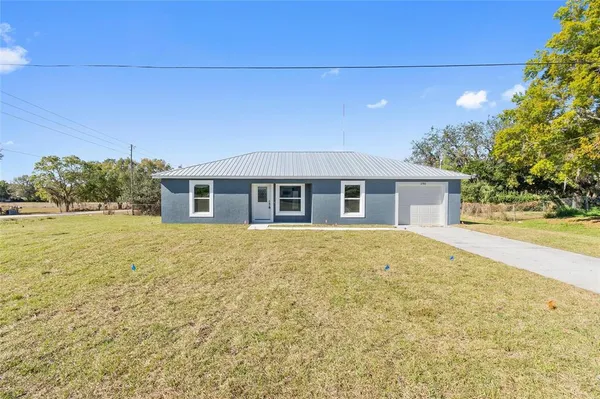 a front view of house with yard and trees in the background