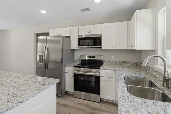 a kitchen with stainless steel appliances granite countertop a sink stove and refrigerator