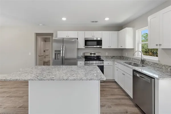 a kitchen with stainless steel appliances granite countertop a sink stove and refrigerator
