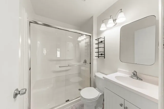 a bathroom with a sink a toilet a mirror and shower