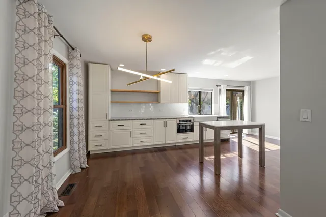 a open kitchen with white cabinets and wooden floor
