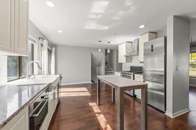 a kitchen with stainless steel appliances granite countertop a table chairs a sink and a refrigerator