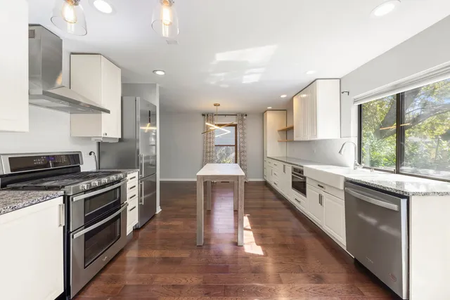 a large kitchen with stainless steel appliances granite countertop a stove a sink and a microwave