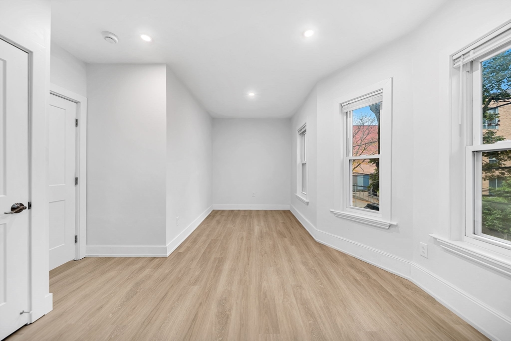 92 Willow Street, Unit 2 Cambridge, MA 02141 - Photo 17 of 20 an empty room with wooden floor and windows