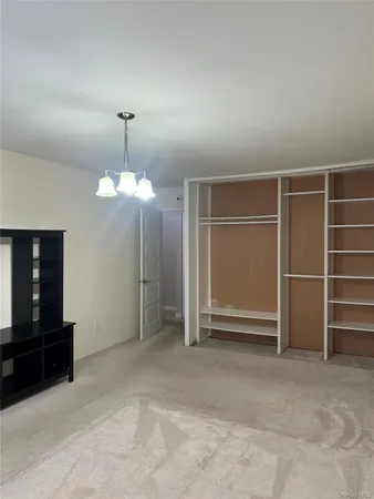 a view of an empty room with a fireplace and a chandelier fan