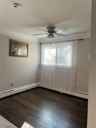 an empty room with wooden floor chandelier fan and windows
