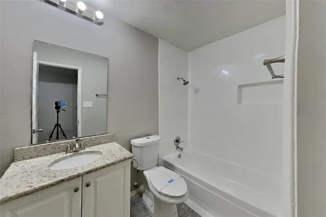 a bathroom with a granite countertop toilet a sink and a bathtub
