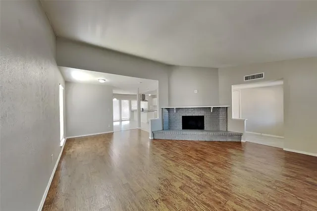 an empty room with wooden floor and fireplace