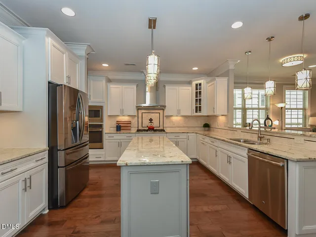 a kitchen with granite countertop a refrigerator a sink dishwasher a stove and white cabinets with wooden floor