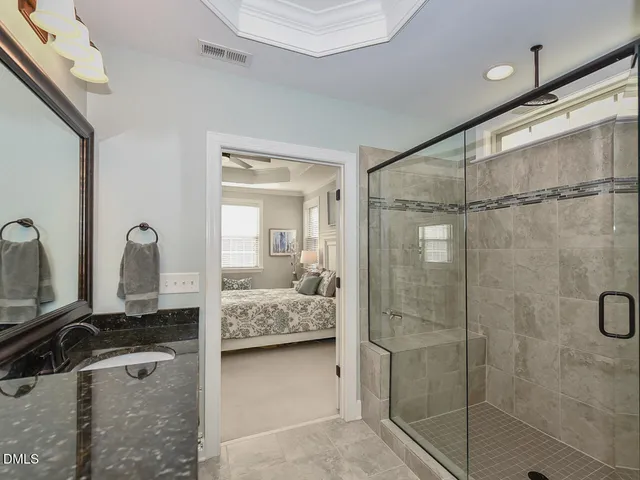 a en suite bathroom with a granite countertop sink mirror and shower