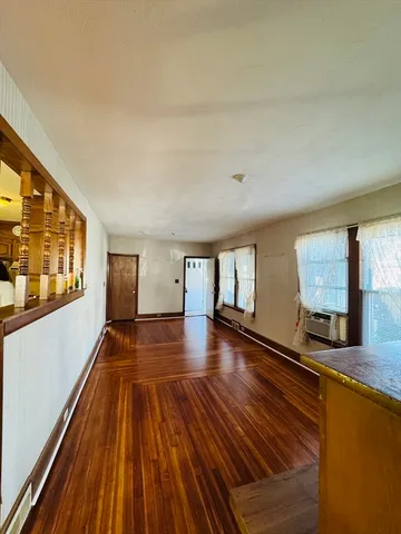 a view of an empty room with window and wooden floor