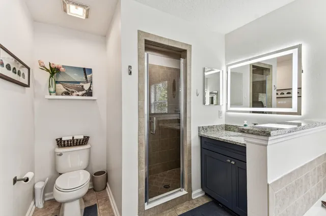 a bathroom with a granite countertop sink a toilet and shower
