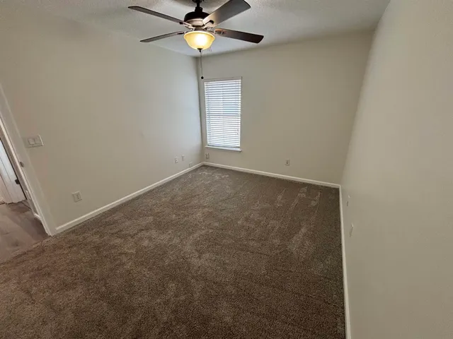 a living room with furniture ceiling fan and a large window