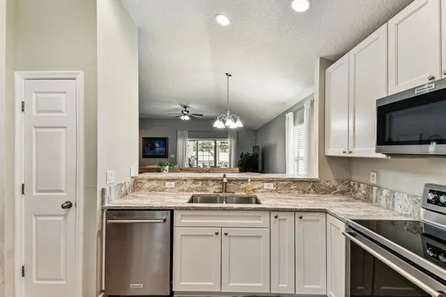 a kitchen with granite countertop a sink stainless steel appliances and white cabinets