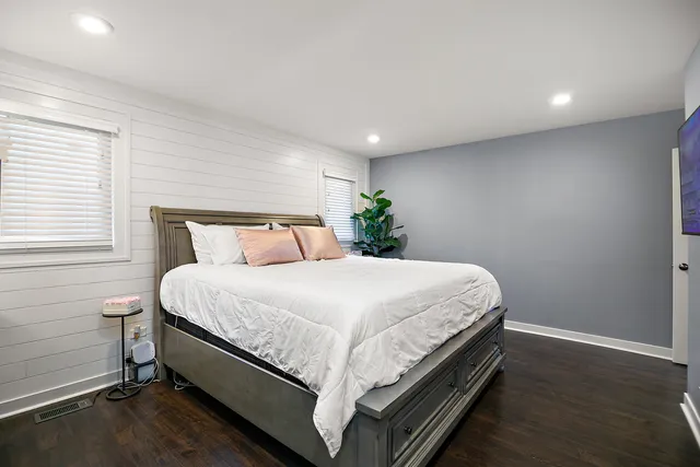 a bed sitting in a spacious bedroom next to a window