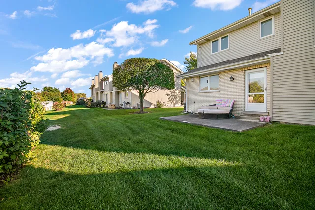a view of a white house with a big yard and large trees