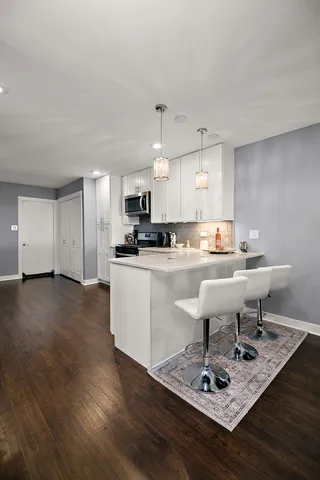 a kitchen with a sink a stove a refrigerator and white cabinets with wooden floor