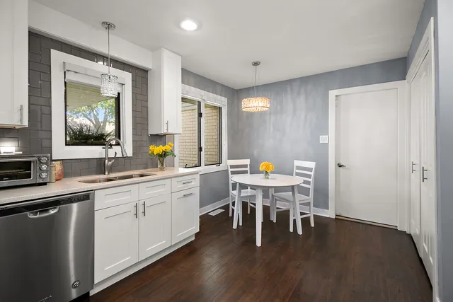 a kitchen with a dining table chairs sink and granite counter tops