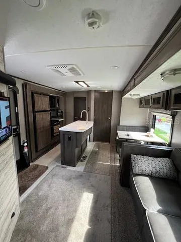 a living room with stainless steel appliances furniture and a kitchen view