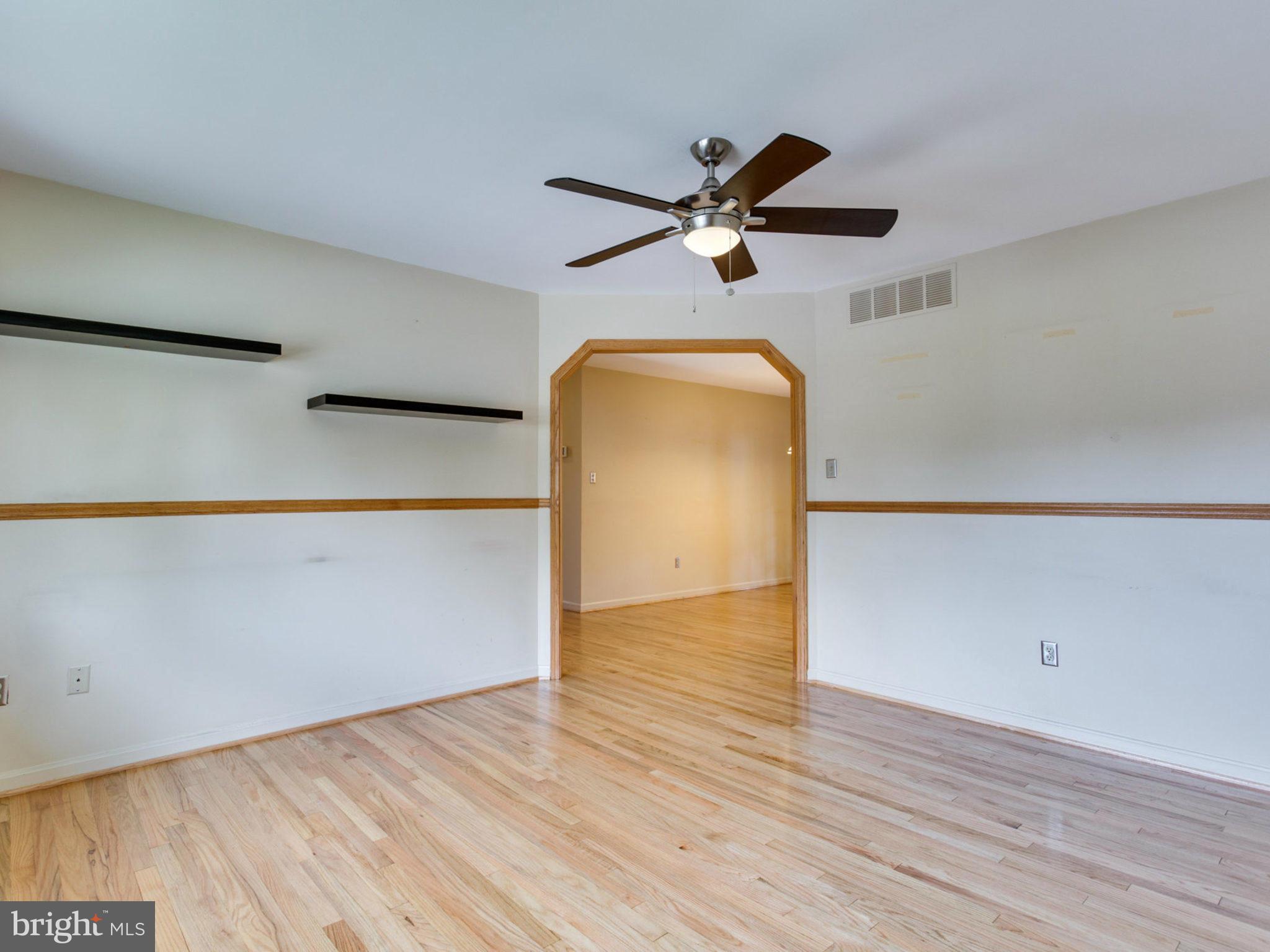 415 Rockway Road Catonsville, MD 21228 - Photo 4 of 30 an empty room with wooden floor a ceiling fan and a window