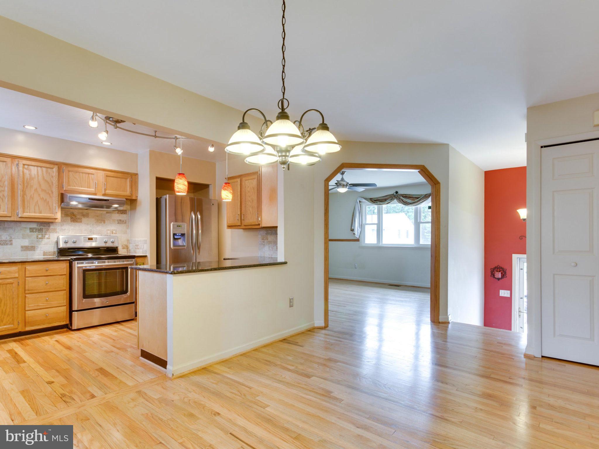 415 Rockway Road Catonsville, MD 21228 - Photo 6 of 30 a kitchen with stainless steel appliances granite countertop a refrigerator a sink dishwasher a kitchen island with wooden floor and chandelier