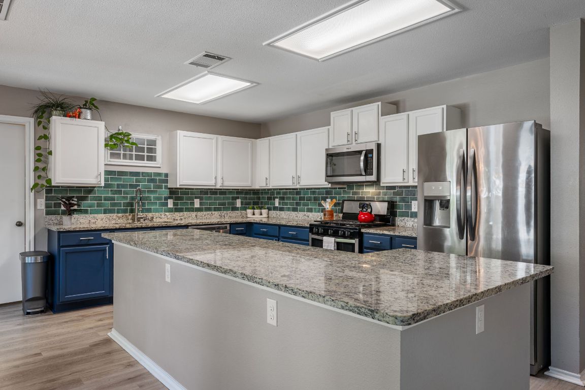 1607 Azalea Drive Cedar Park, TX 78613 - Photo 10 of 40 a kitchen with granite countertop a refrigerator a sink a stove a microwave and wooden cabinets