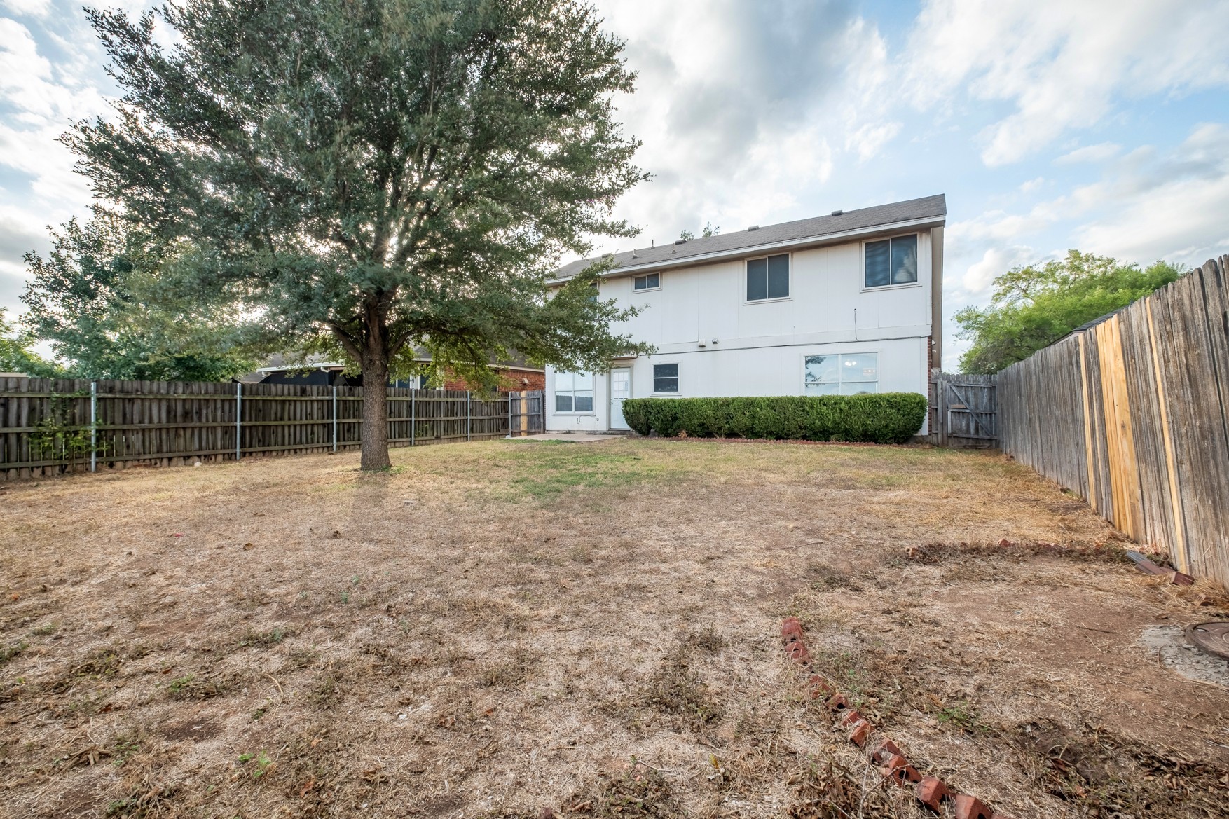 3709 Crownover Street Austin, TX 78725 - Photo 26 of 26 The property features a fenced yard with a mature tree and a well-maintained shrub border along the rear of the home