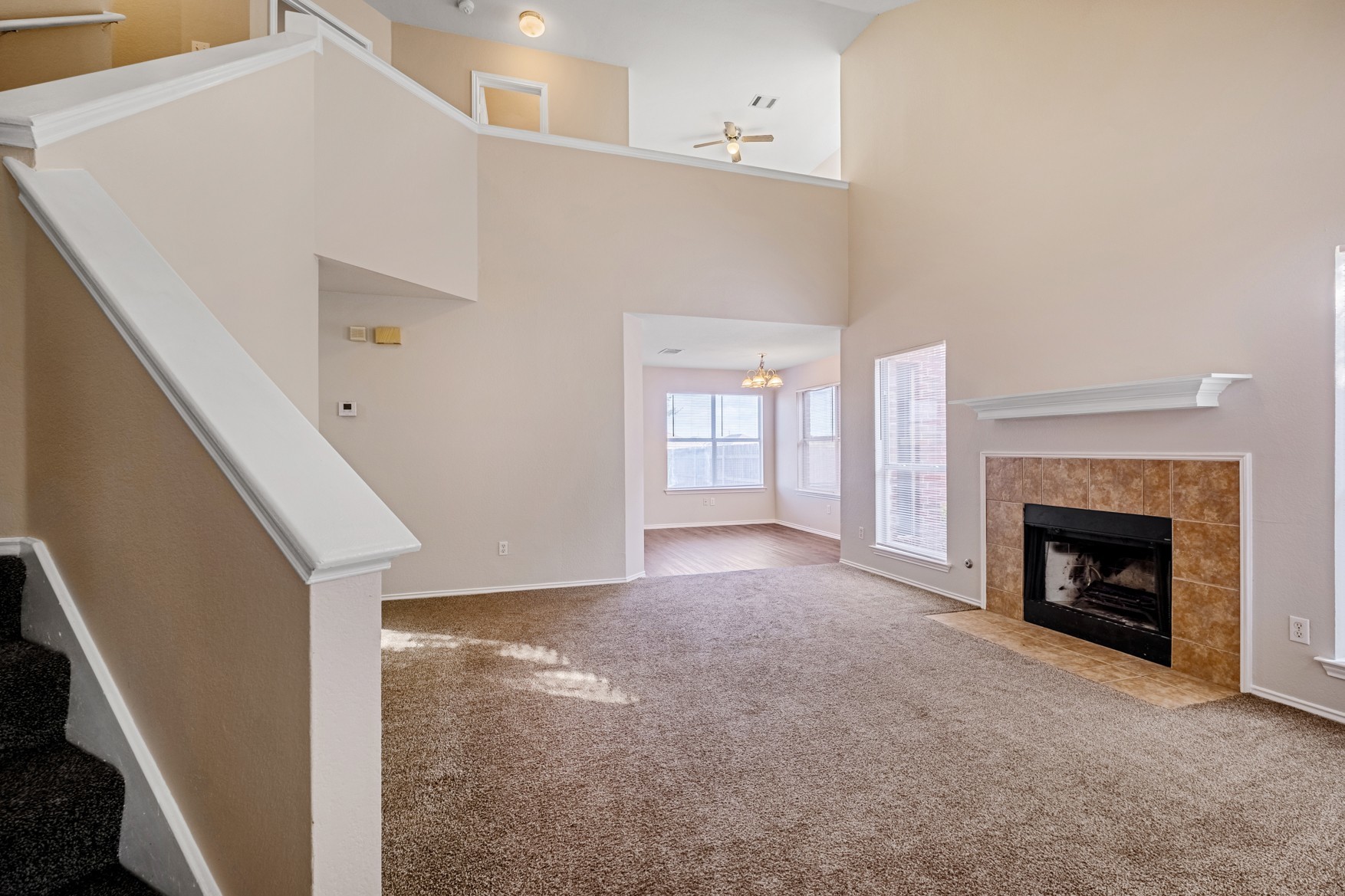 3709 Crownover Street Austin, TX 78725 - Photo 4 of 26 Spacious living area featuring high ceilings, a fireplace with a tiled surround, carpeted floors, and large windows providing ample natural light