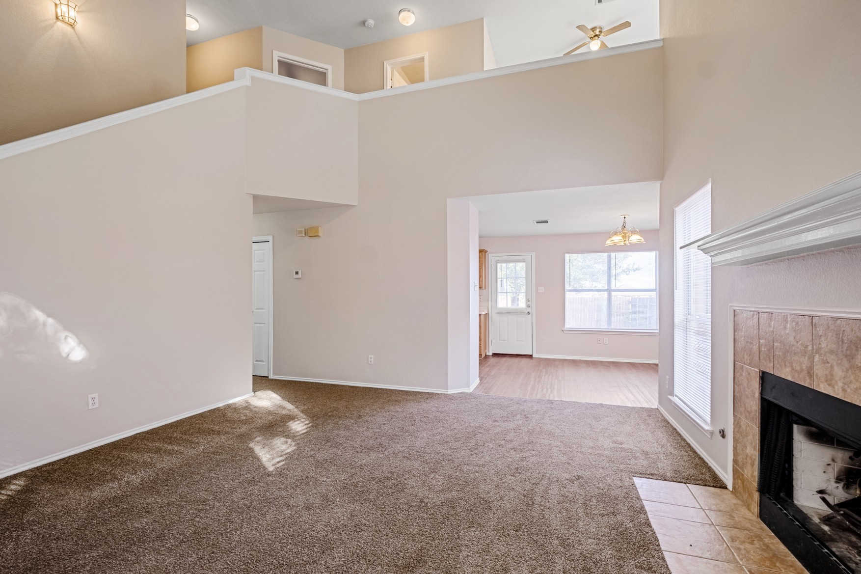 3709 Crownover Street Austin, TX 78725 - Photo 5 of 26 Living area with high ceilings, carpet flooring, and a fireplace with a tiled hearth and mantel