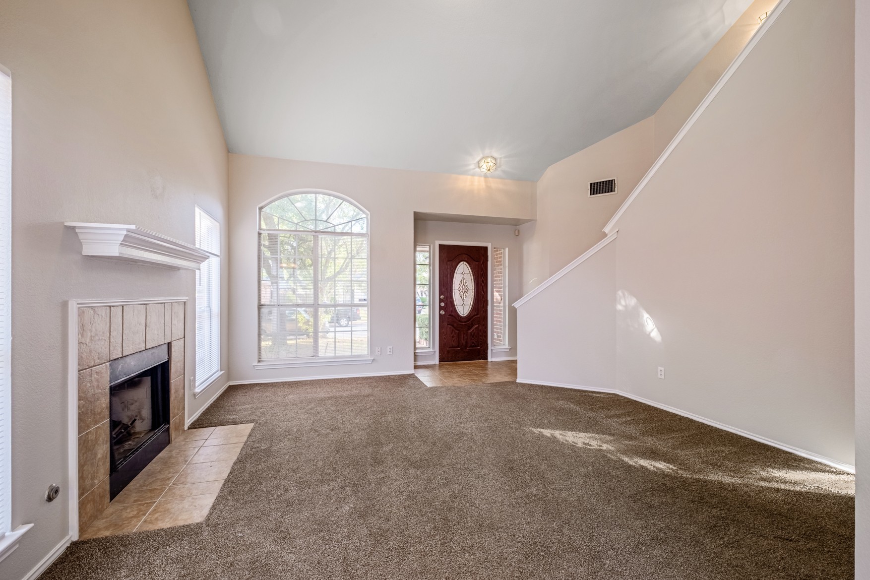 3709 Crownover Street Austin, TX 78725 - Photo 6 of 26 Spacious living area featuring a fireplace with a tile surround, an arched window, and carpeted flooring