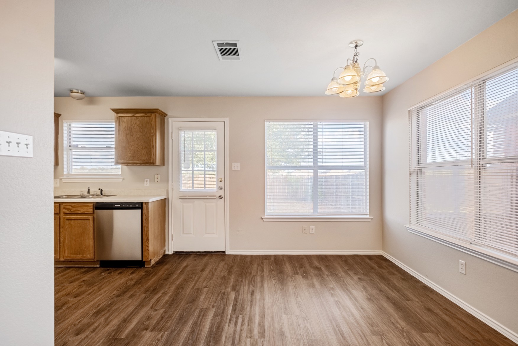 3709 Crownover Street Austin, TX 78725 - Photo 7 of 26 This dining area features wood-look flooring, a modern chandelier, and ample natural light from two large windows with blinds