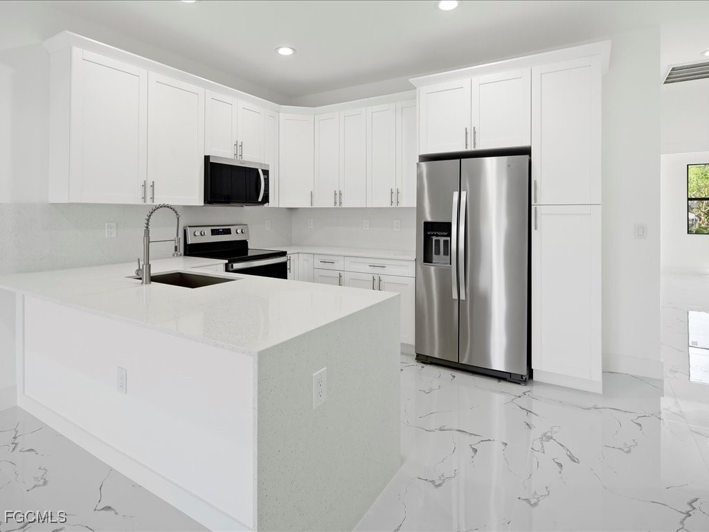 5210 28th Street Southwest Lehigh Acres, FL 33973 - Photo 6 of 12 a kitchen with a refrigerator a microwave a sink and a stove