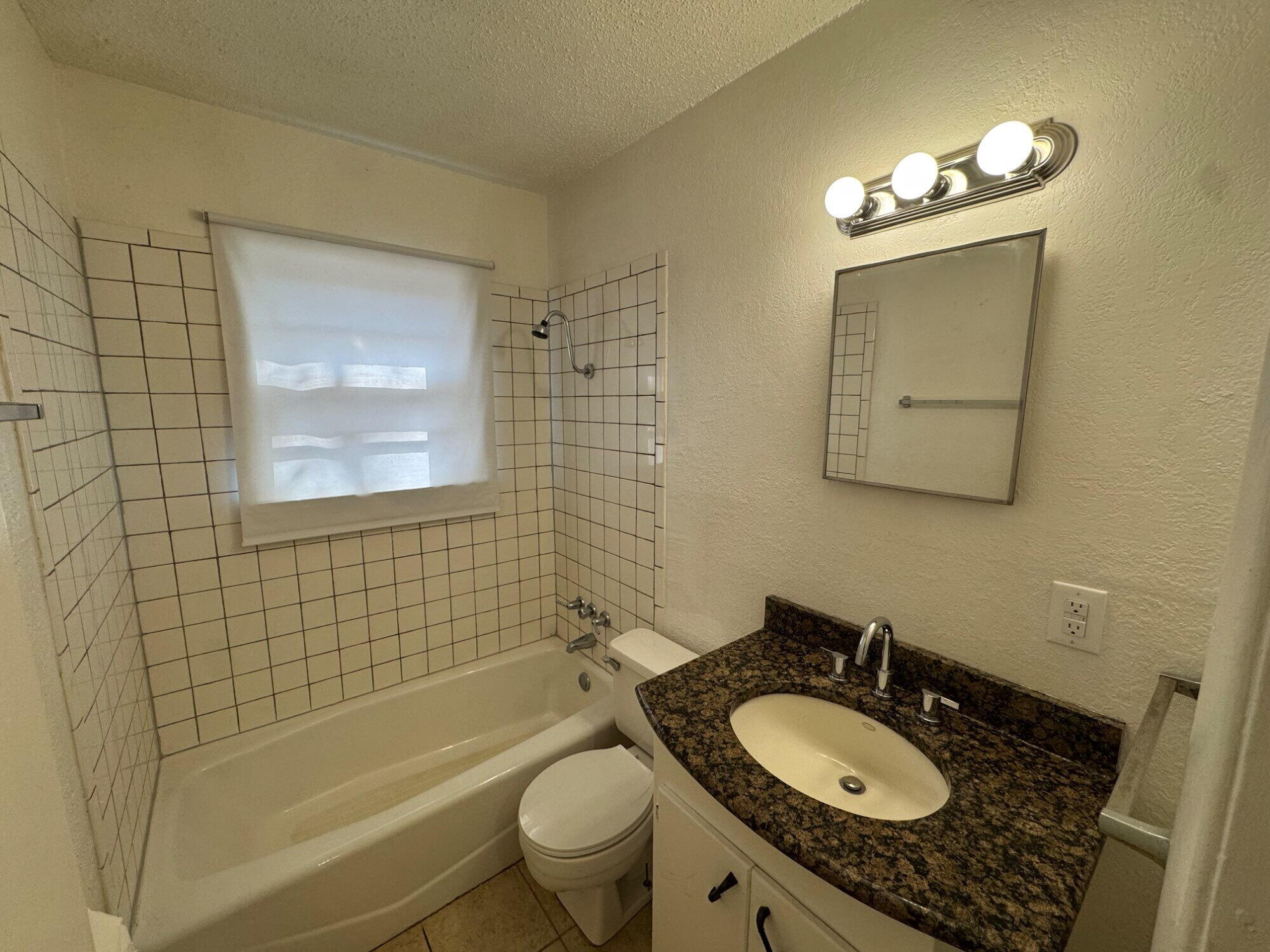 2208 35th Street, Unit B Lubbock, TX 79412 - Photo 6 of 9 a bathroom with a granite countertop sink toilet mirror and shower