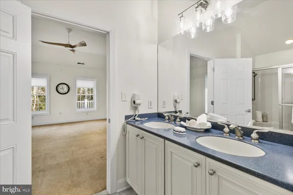 a bathroom with a granite countertop double vanity sink and mirror