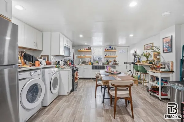 a living room with stainless steel appliances furniture a rug and a kitchen view