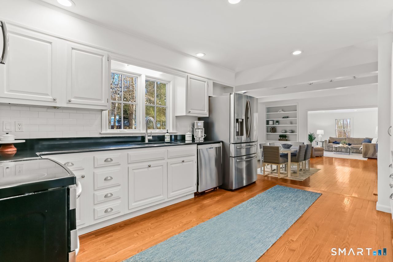 103 Davis Hill Road Weston, CT 06883 - Photo 9 of 37 a kitchen with stainless steel appliances granite countertop a refrigerator a sink dishwasher and white cabinets with wooden floor