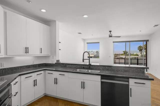 a kitchen with stainless steel appliances granite countertop a sink a stove and white cabinets
