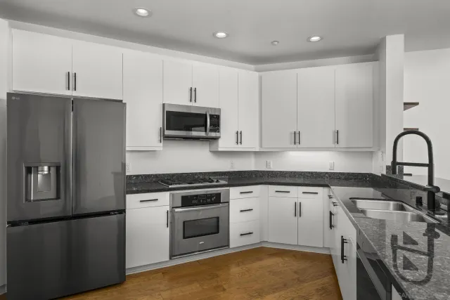 a kitchen with stainless steel appliances granite countertop a stove a sink dishwasher a refrigerator and a stove