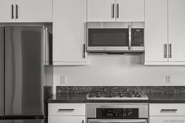 a kitchen with stainless steel appliances granite countertop white cabinets and black stove top oven with granite countertops