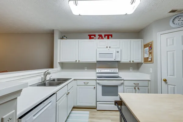 a kitchen with a sink a stove a refrigerator and white cabinets