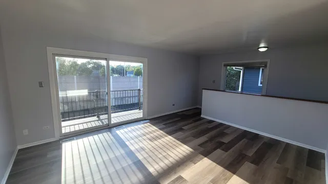 a view of an empty room and wooden floor and a window
