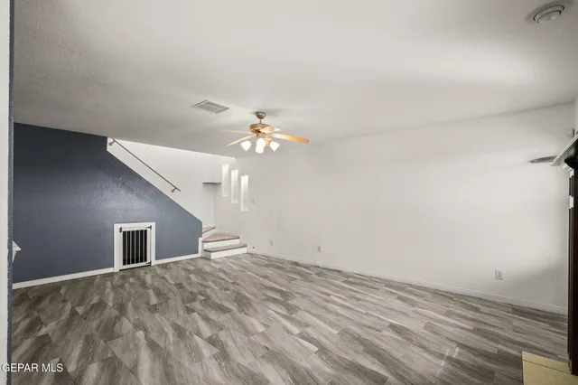 wooden floor in an empty room with a chandelier fan