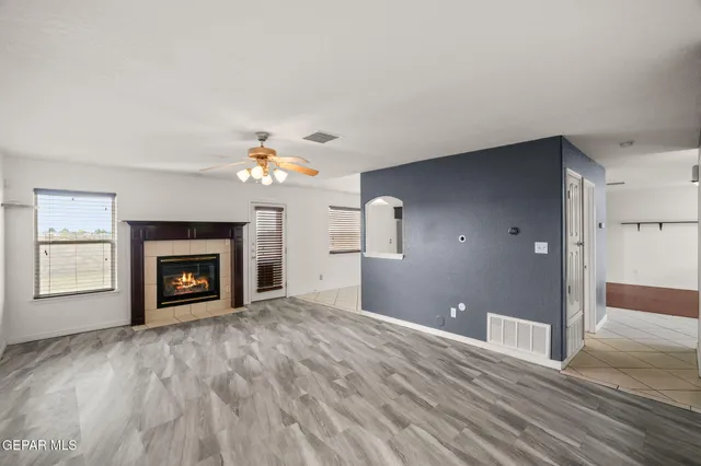 a view of a livingroom with a fireplace a ceiling fan and wooden floor