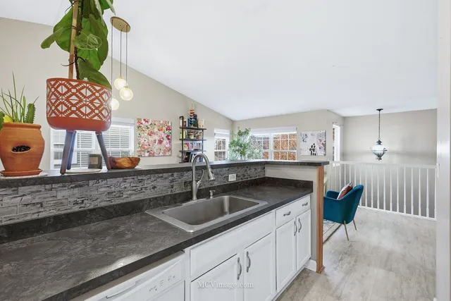 a kitchen with stainless steel appliances granite countertop a sink a stove and a wooden floor