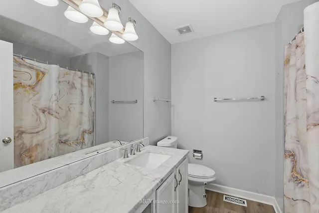 a bathroom with a granite countertop sink a toilet and a shower