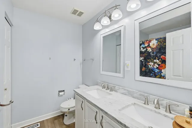 a bathroom with a granite countertop toilet a sink and a mirror