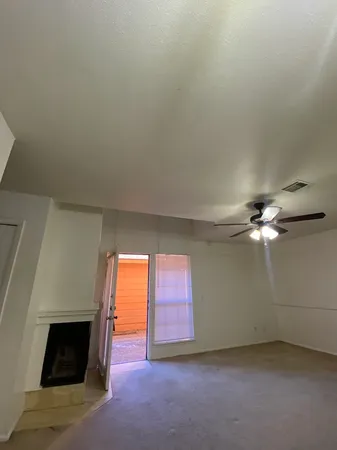 an empty room with windows and fireplace