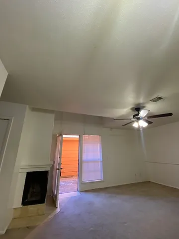 an empty room with windows and fireplace