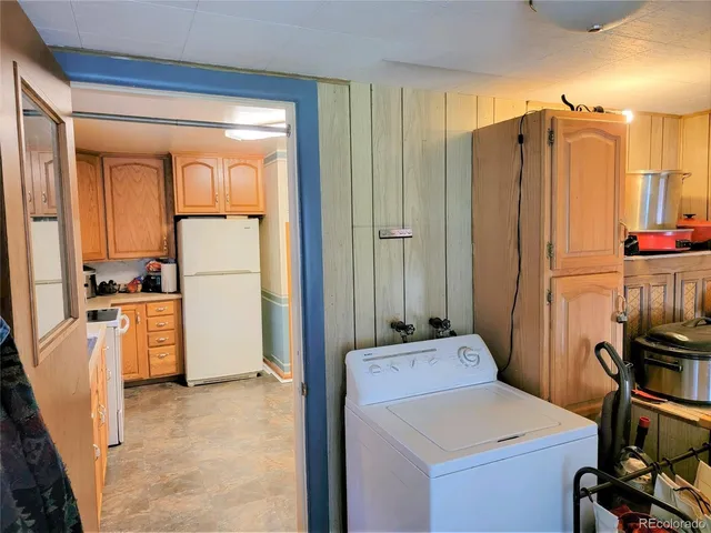 a room with kitchen island a sink a refrigerator and cabinets